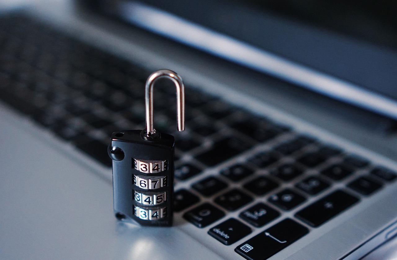 A combination padlock resting on a laptop keyboard, representing the layered security a computer needs beyond a single antivirus app