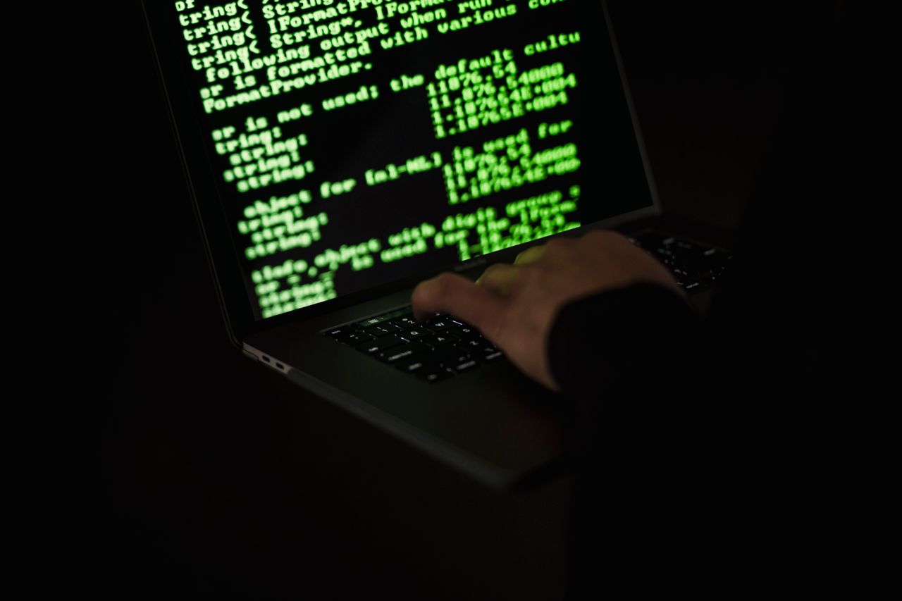 A laptop screen showing lines of code in a dark room